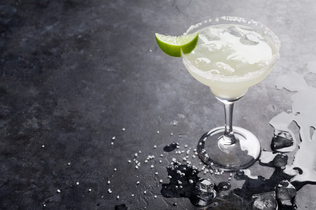 Margarita with a wedge of lime sits on a table.
